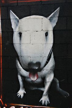 a painting of a dog on the side of a building with its mouth open and tongue out