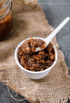 a small white bowl filled with food next to a jar of peanut butter on a table