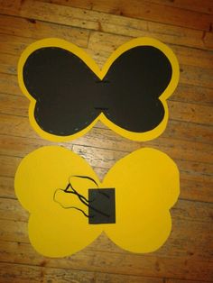 two pieces of paper with black and yellow designs on them sitting on a wooden floor