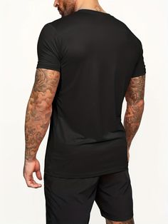 a man in black shirt and shorts looking down at his left arm with tattoos on it