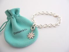 Overview: Here is a gift that she will surely adore! It is shiny, stylish, and super versatile! This piece will make someone REALLY happy! :) Offered for sale is a wonderful Tiffany & Co. Sterling Silver and Pink Enamel Daisy Charm Bracelet. Hanging from its bright Tiffany silver chain is a very pretty Pink Enamel Daisy charm! A classic Tiffany piece that any girl will adore! The Daisy charm hangs from its Sterling Silver Tiffany clasp - it is removable from the bracelet and thus allows you to w Luxury Sterling Silver Charm Bracelet Gift, Luxury Sterling Silver Charm Bracelet As A Gift, Luxury White Gold Charm Bracelet Gift, Luxury Flower-shaped Bracelets As Gift, Elegant Polished Charm Bracelet Gift, Elegant Charm Bracelet As Gift With Polished Finish, Elegant Polished Charm Bracelet As Gift, Elegant Polished Finish Charm Bracelet Gift, White Gold Bracelet With Flower Charm Gift