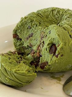 a white plate topped with green dessert next to a spoon