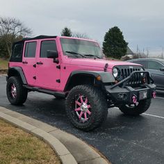 a pink jeep is parked in a parking lot