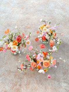 three vases filled with different types of flowers on the ground next to each other