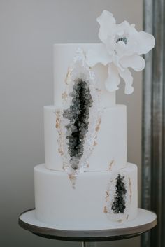 a white wedding cake with black and white frosting on the top, decorated with flowers