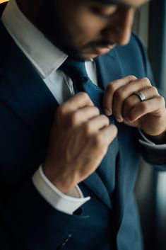 a man in a suit adjusting his tie