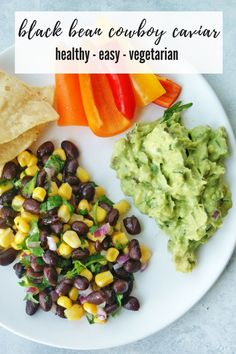 a white plate topped with black beans, guacamole and tortilla chips