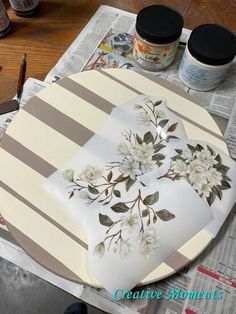 a plate with flowers painted on it sitting on top of a table next to paintbrushes