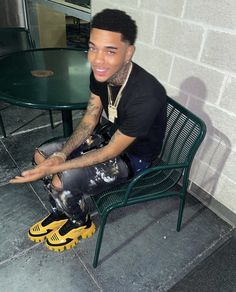 a young man sitting on top of a green chair next to a table with a yellow shoe