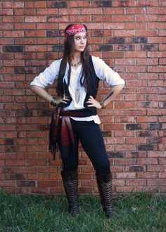 a woman standing in front of a brick wall with her hands on her hipss