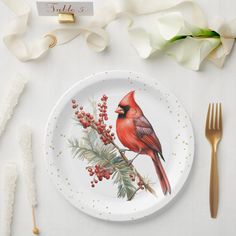 a white plate topped with a red cardinal on top of a table next to utensils