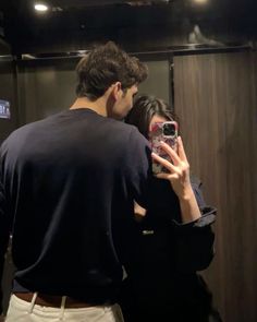 a man and woman taking a selfie in front of a mirror