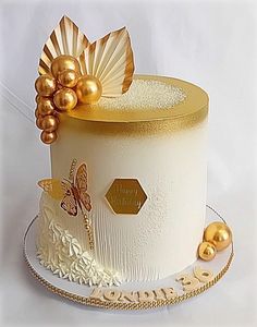 a white cake with gold decorations on the top and sides, sitting on a plate