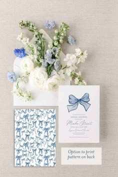 the wedding stationery is laid out with flowers and blue ribbon on it's envelope