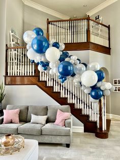 a living room filled with furniture and balloons floating from the ceiling next to a stair case