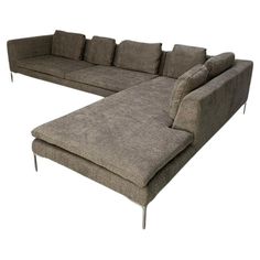 a large sectional couch sitting on top of a white floor next to a footstool