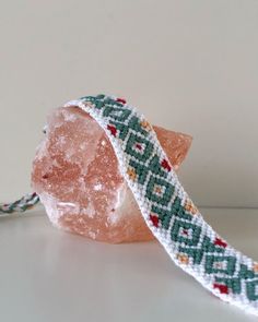 a beaded bracelet sitting on top of a piece of pink quartz next to a rock