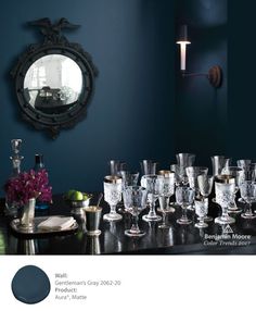 there are many glasses on the table in front of the mirror and wall sconces