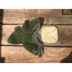 a crocheted green hat and a white knitted object on a wooden surface