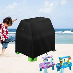 a young boy playing on the beach with an inflatable water table and chairs