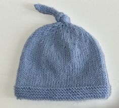 a blue knitted hat with a knot at the top