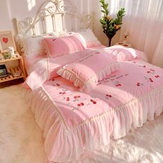 a bed with pink comforters and pillows in a room next to a white window