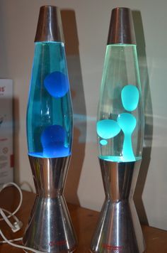 two glass vases sitting on top of a table next to each other with blue balls in them