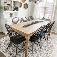 a dining room table with black chairs and white walls