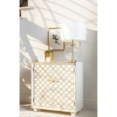 a white and gold cabinet with a lamp next to it