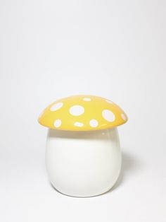 a white and yellow mushroom shaped container with polka dots on the top, sitting in front of a white background