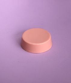 a pink pill on a purple surface with a white cap in the middle and an orange button at the top