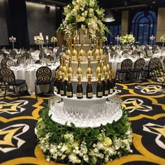 there are many bottles of champagne on the table in this banquet room with white and green flowers