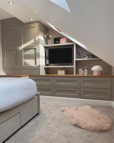 an attic bedroom with built - in entertainment center and bed