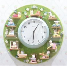 a green clock with many little toys on it's face and around the clock