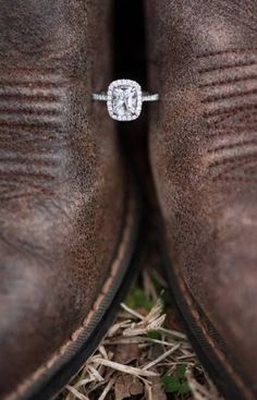 a close up of a pair of brown boots with a diamond ring