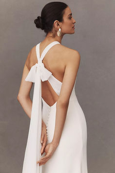 a woman wearing a white dress with a bow back