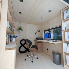 a computer desk and chair in a small room with bookshelves on the wall