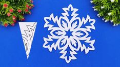 a snowflake cut out on a blue background next to potted plants and flowers