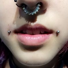 a close up of a person with piercings on their nose and eye ring in front of her face