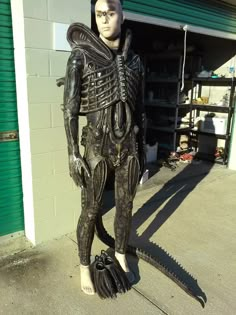 a statue of an alien standing in front of a garage