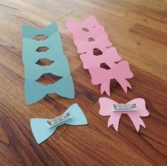 three pieces of paper cut out to look like bows on a wooden floor with clips