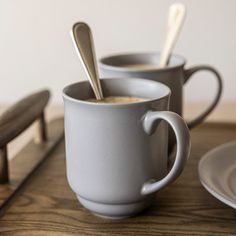 two mugs with spoons in them sitting on a table