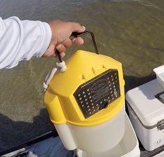 a person is holding a yellow and white device in their hand while standing on a boat