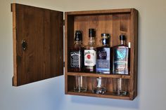 an open wooden box with liquor bottles and shot glasses in it on top of a counter