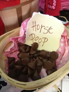 a wooden basket filled with lots of chocolate candies next to a sign that says horse poop