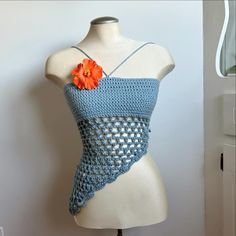 a crocheted top on a mannequin with an orange flower in the center