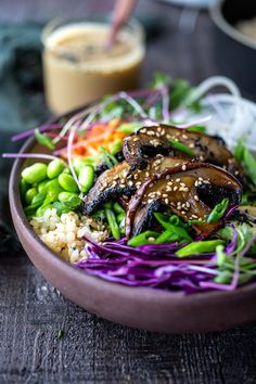 a bowl filled with rice and vegetables on top of a wooden table