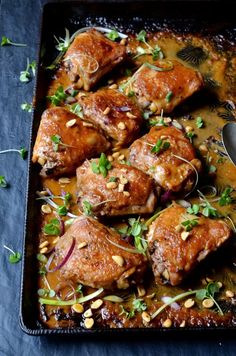 a pan filled with meat covered in sauce and garnished with herbs