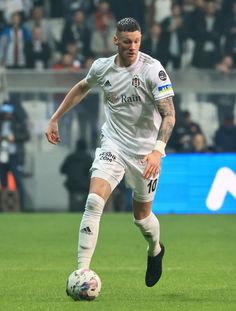 a soccer player in action on the field during a game with fans watching from the stands