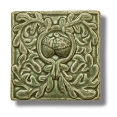 a square tile with an intricate design on the front and back side, in light green